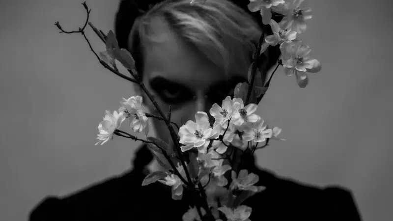 A black and white photo of a woman holding flowers.