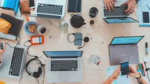 A social gathering with people working on laptops at a table.