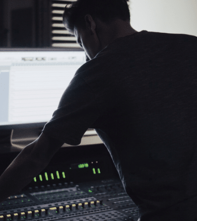 A man working on a mixing console in a dark room, planning.