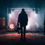 A crowd of people gathering in front of a stage at night.