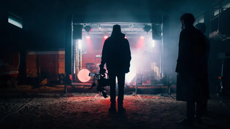 A crowd of people gathering in front of a stage at night.