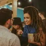 A woman with dreadlocks engaging in a conversation with a man at a community party.