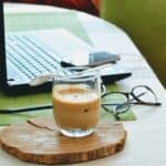 Managers working during quarantine with a cup of coffee on a wooden board next to a laptop.