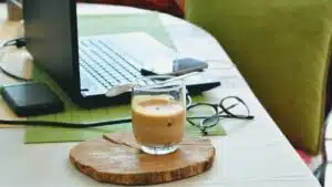 Managers working during quarantine with a cup of coffee on a wooden board next to a laptop.