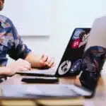 A publicist working at a desk with two laptops.