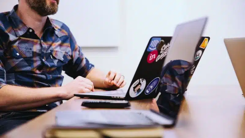A publicist working at a desk with two laptops.