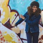 A woman smiling in front of a wall with graffiti for press photos.