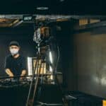 A dj live streaming in front of a camera in a dark room.