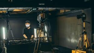 A dj live streaming in front of a camera in a dark room.