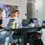 A team of women executing a marketing campaign while working at a table with laptops.