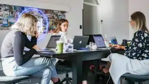 A team of women executing a marketing campaign while working at a table with laptops.