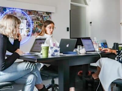 A team of women executing a marketing campaign while working at a table with laptops.