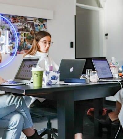 A team of women executing a marketing campaign while working at a table with laptops.