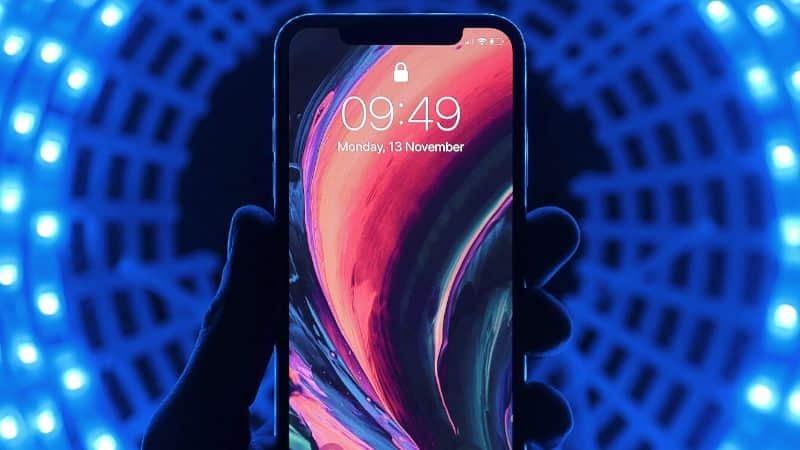 A person is holding an iPhone XR in front of a blue light to capture the best time to post on TikTok.