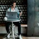 A man managing tasks at a table with a laptop.