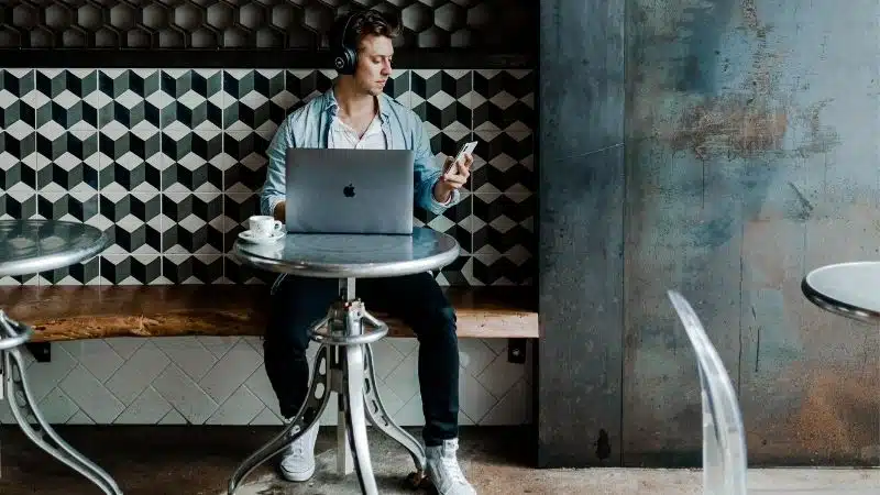 A man managing tasks at a table with a laptop.