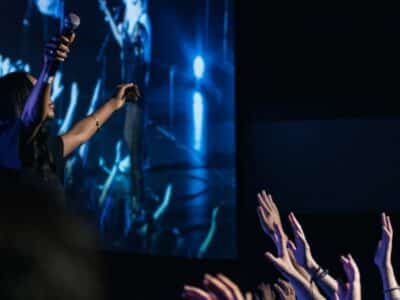 A group of people at a concert, enthusiastically raising their hands in support, creating an electrifying ambiance.