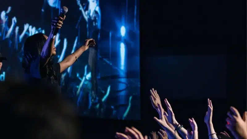 A group of people at a concert, enthusiastically raising their hands in support, creating an electrifying ambiance.