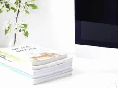 A stack of books on a desk next to a computer.