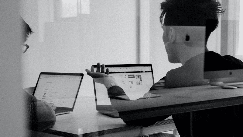 A black and white legal photo of two people working on laptops.