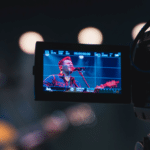 A video camera capturing a man singing, aiming to sell more merch.