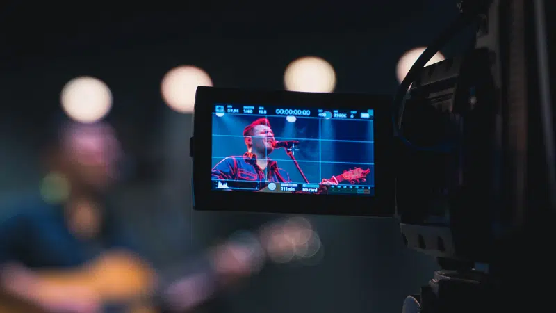 A video camera capturing a man singing, aiming to sell more merch.