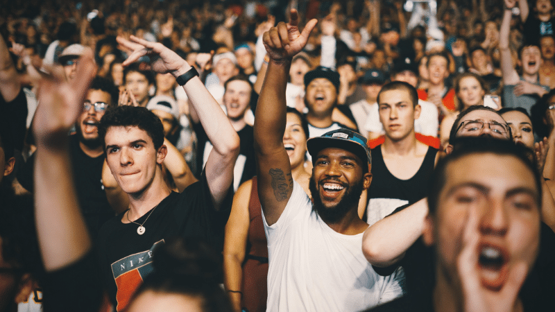A crowd of people cheering at a concert during a music industry podcast event.