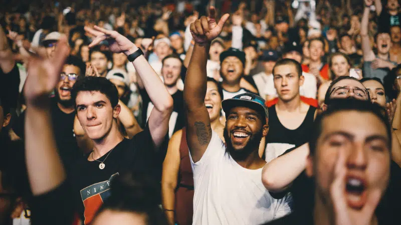 A crowd of people cheering at a concert during a music industry podcast event.