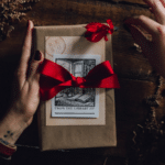 A woman's hand holding a gift box with red roses, offering holiday marketing tips.