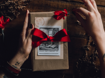 A woman's hand holding a gift box with red roses, offering holiday marketing tips.