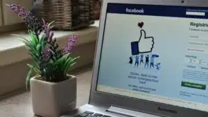 A laptop with a Facebook sign on it is sitting on a table, playing music videos.