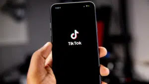 A person showcasing the tikk logo on a smartphone to increase views on TikTok.