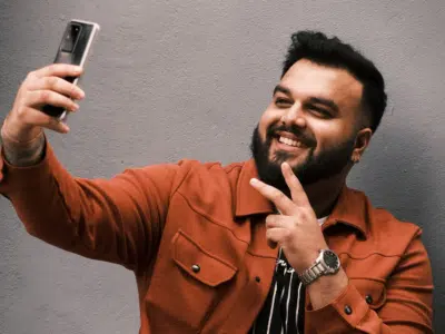 A man is taking a selfie for TikTok with his phone.