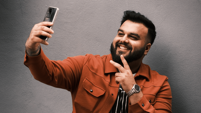 A man is taking a selfie for TikTok with his phone.