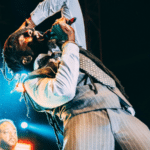 A man in a suit and tie singing into a microphone at a mechanical licensing event.