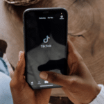 A person holding a phone with the Tinder app on it, analyzing TikTok data.