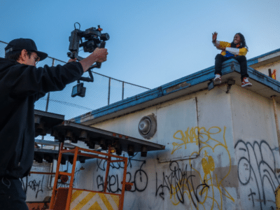 A man capturing a music video on top of a building with graffiti.
