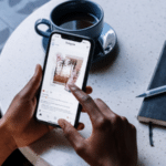 A woman holding a phone and a notebook at a table promoting an Instagram Merch Shop.