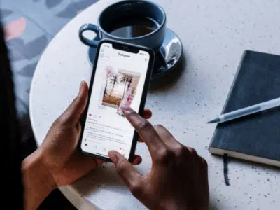 A woman holding a phone and a notebook at a table promoting an Instagram Merch Shop.