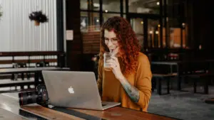 A woman sitting at a table with a laptop working on email marketing.