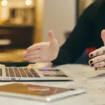 A woman in the music industry is sitting at a table with a laptop.