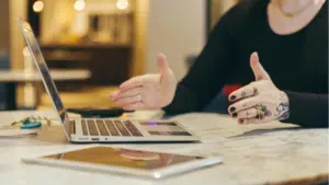 A woman in the music industry is sitting at a table with a laptop.