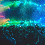 A crowd of people dancing to DJ's at a music festival.