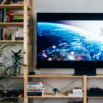 A living room with a tv on top of a bookshelf, showcasing royalties.