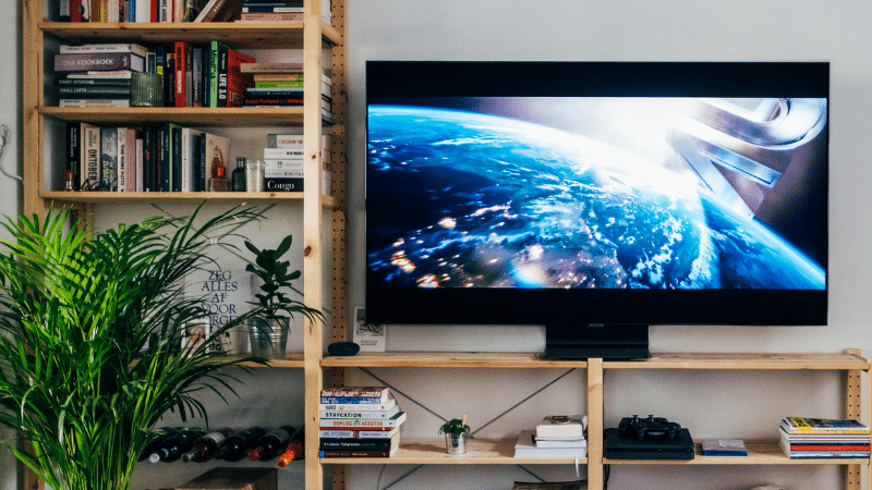 A living room with a tv on top of a bookshelf, showcasing royalties.