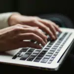 Hands typing on a SplitShare-enhanced laptop keyboard.