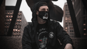 A man wearing a black hoodie and a face mask to prevent COVID.