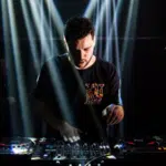 A man promoting music while djing in front of a light beam.