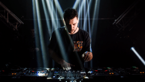 A man promoting music while djing in front of a light beam.