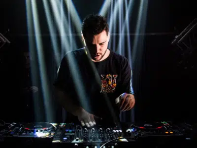 A man promoting music while djing in front of a light beam.